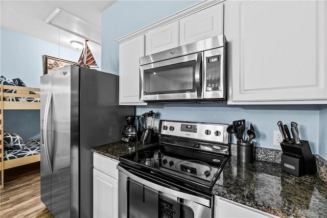 14915 Island Village Dr, Corpus Christi, TX 78418 - kitchen with appliances with stainless steel finishes, white cabinets, wood finished floors, and dark stone counters