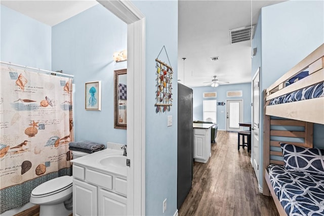 14915 Island Village Dr, Corpus Christi, TX 78418 - full bathroom featuring vanity, wood finished floors, toilet, ceiling fan, and curtained shower