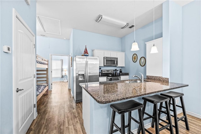 14915 Island Village Dr, Corpus Christi, TX 78418 - kitchen featuring appliances with stainless steel finishes, wood finished floors, dark stone counters, a peninsula, and a kitchen bar