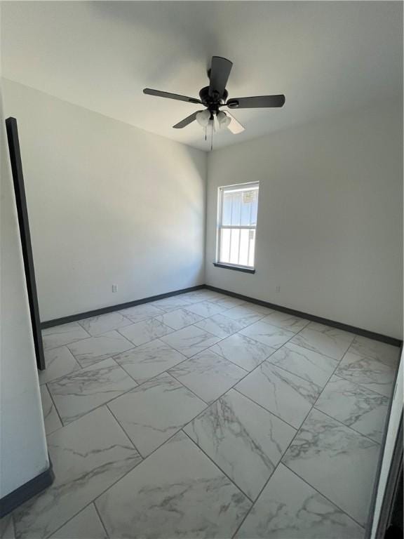 unfurnished room with baseboards, marble finish floor, and a ceiling fan