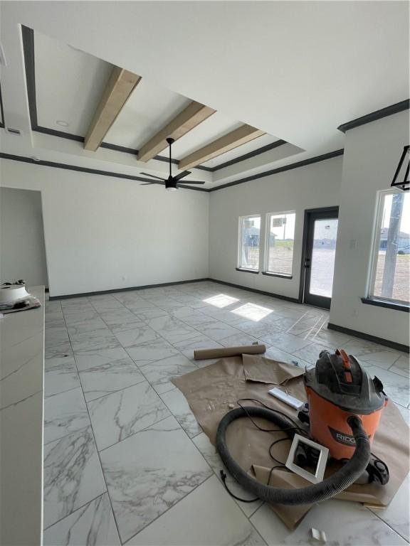 unfurnished living room featuring baseboards, a raised ceiling, marble finish floor, and ornamental molding