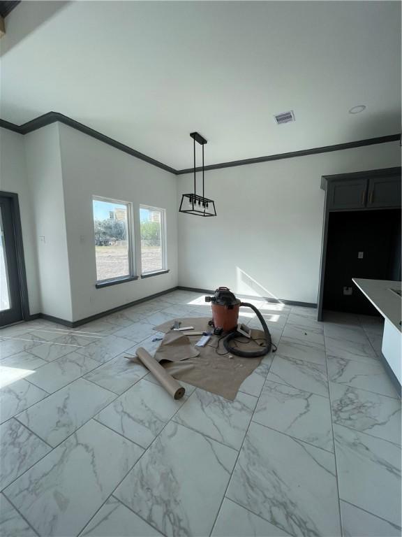 unfurnished dining area featuring visible vents, marble finish floor, crown molding, and baseboards