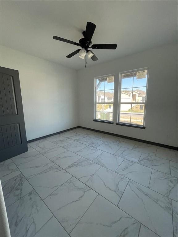 spare room featuring baseboards, marble finish floor, and ceiling fan