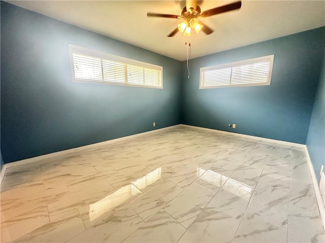 empty room featuring baseboards, marble finish floor, and ceiling fan
