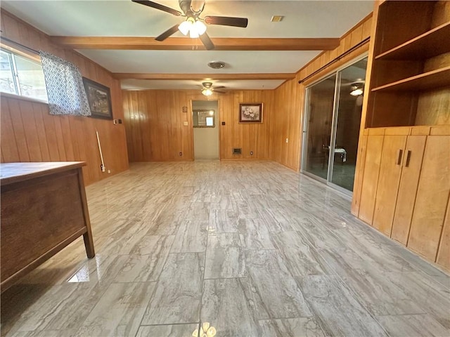 spare room with beam ceiling, wood walls, a ceiling fan, and light wood-style floors