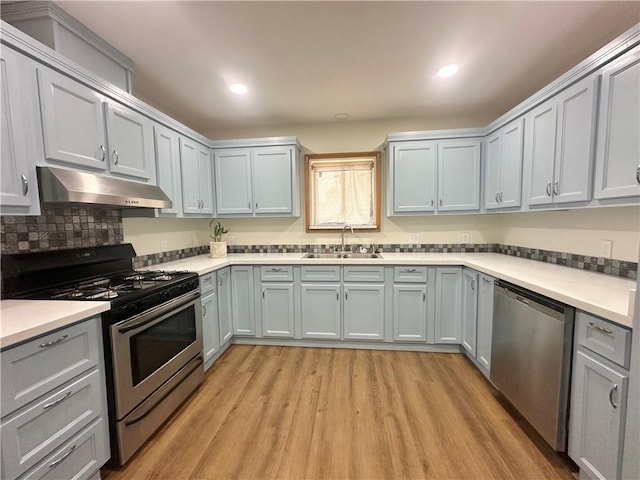 kitchen with a sink, light wood-type flooring, under cabinet range hood, appliances with stainless steel finishes, and recessed lighting