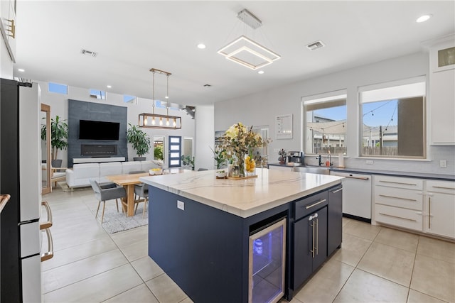 15130 Reales Dr, Corpus Christi, TX 78418 - kitchen featuring beverage cooler, dishwashing machine, freestanding refrigerator, open floor plan, and white cabinetry