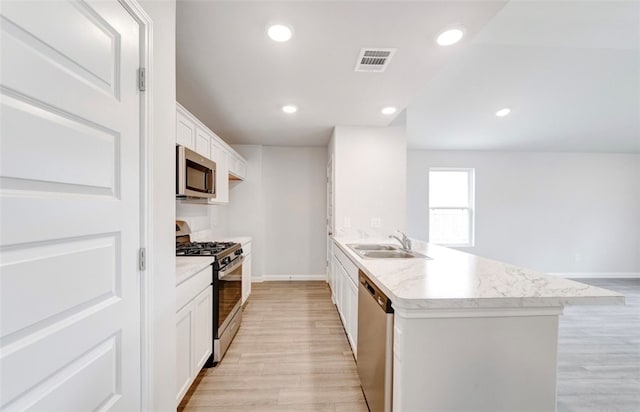 kitchen featuring light hardwood / wood-style flooring, sink, an island with sink, white cabinetry, and appliances with stainless steel finishes