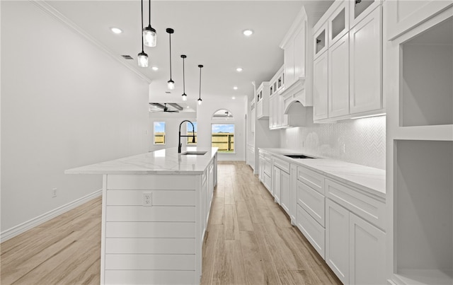 kitchen featuring ceiling fan, sink, a kitchen island with sink, hanging light fixtures, and decorative backsplash