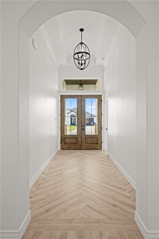 entrance foyer featuring a tray ceiling, french doors, a chandelier, and ornamental molding