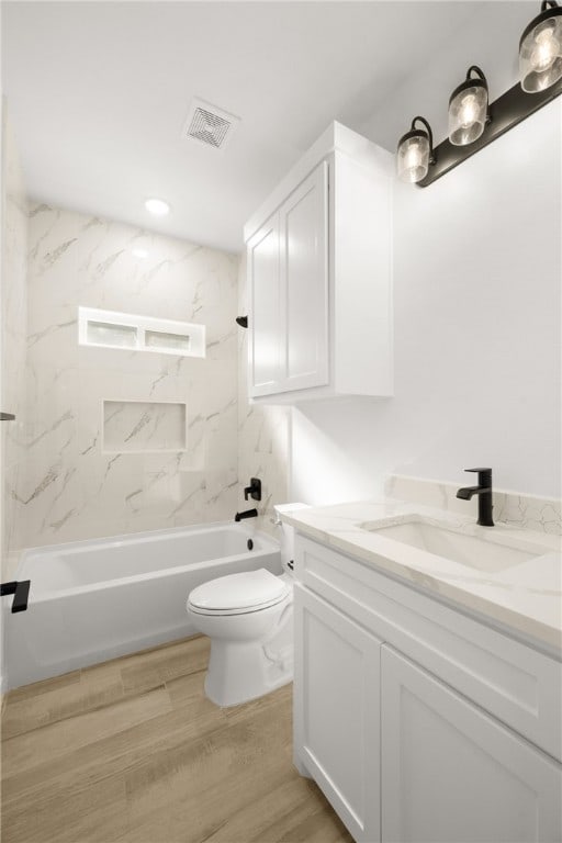 full bathroom featuring hardwood / wood-style flooring, vanity, toilet, and tiled shower / bath