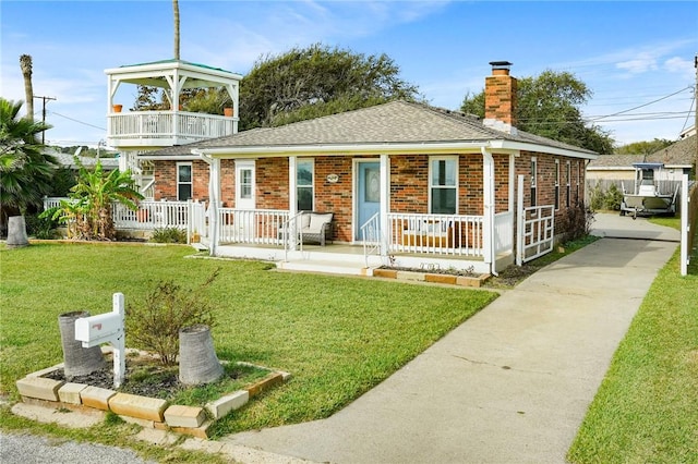 view of front of house featuring a balcony and a front lawn