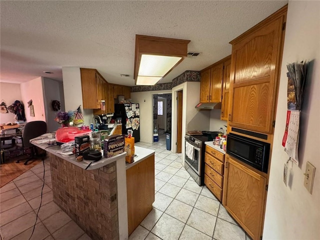 kitchen with black appliances, a kitchen bar, light tile patterned floors, kitchen peninsula, and a textured ceiling