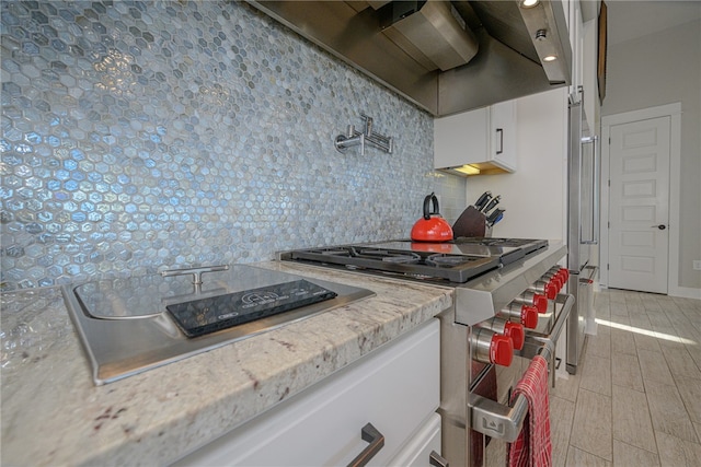 kitchen featuring light stone countertops, decorative backsplash, white cabinetry, and light hardwood / wood-style floors