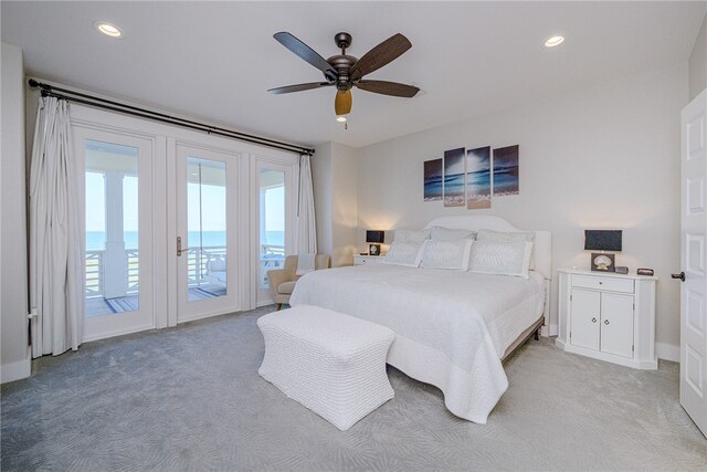 carpeted bedroom featuring access to outside, a water view, and ceiling fan