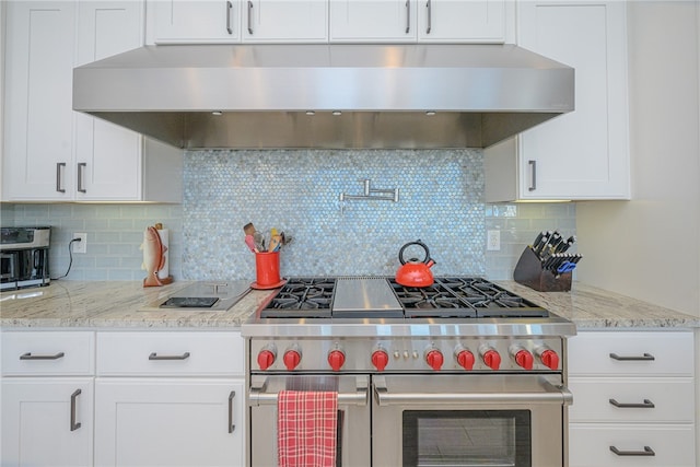 kitchen featuring range with two ovens, white cabinetry, exhaust hood, and tasteful backsplash