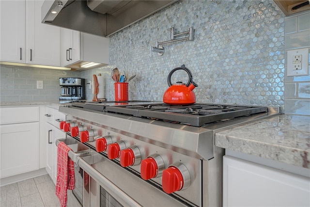 kitchen featuring backsplash, white cabinets, light stone countertops, and high end stainless steel range oven