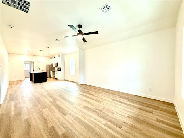 unfurnished living room with light wood-type flooring, ceiling fan, and sink