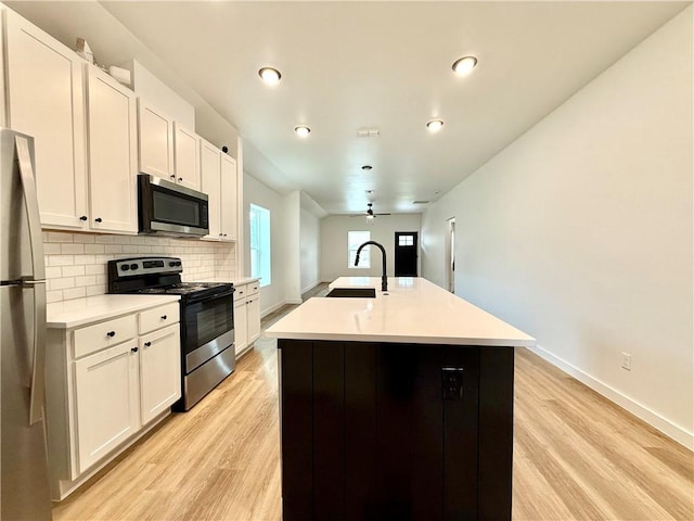 kitchen featuring a kitchen island with sink, sink, ceiling fan, white cabinetry, and stainless steel appliances