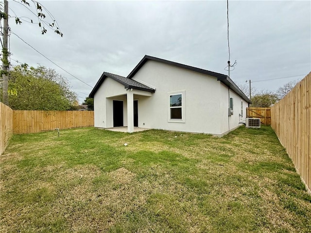 rear view of house with central AC unit and a lawn