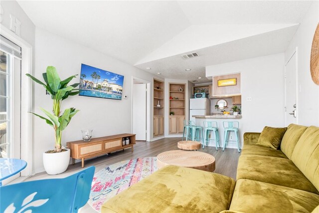 kitchen with visible vents, a kitchen breakfast bar, a textured ceiling, white appliances, and a peninsula