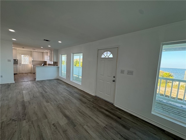 unfurnished room with dark wood-type flooring and a water view