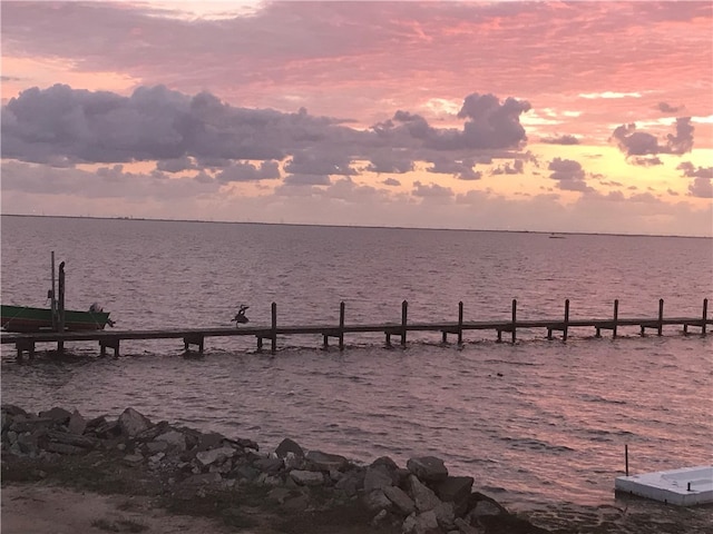 patio terrace at dusk with a beach view and a water view