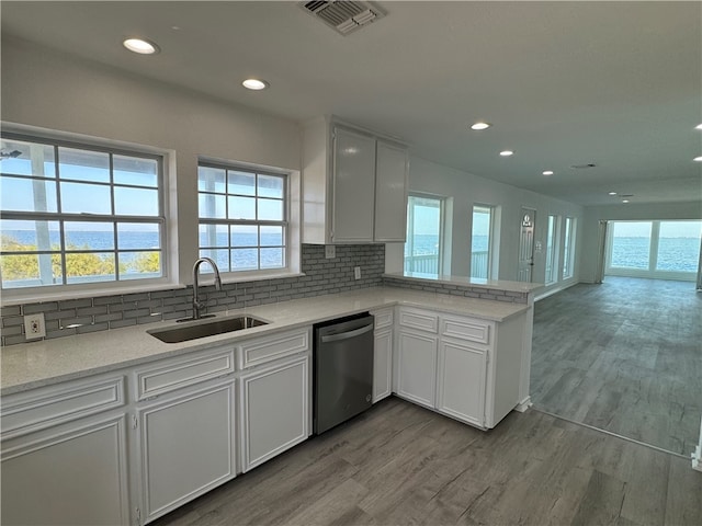 kitchen with light wood-type flooring, decorative backsplash, sink, white cabinets, and stainless steel dishwasher