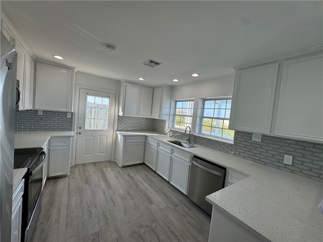 kitchen with decorative backsplash, sink, stainless steel dishwasher, light stone countertops, and white cabinetry