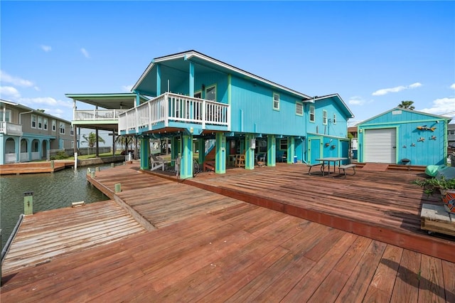 back of house with an outdoor structure, a deck with water view, and a storage unit