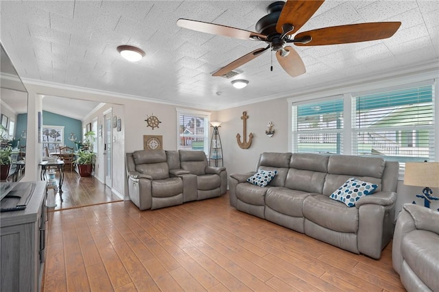 living area with ceiling fan, ornamental molding, wood finished floors, and visible vents
