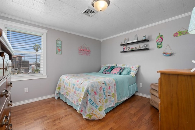 bedroom with ornamental molding, wood finished floors, and visible vents