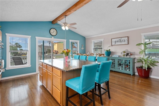 kitchen with plenty of natural light, ceiling fan, wood finished floors, and a kitchen bar
