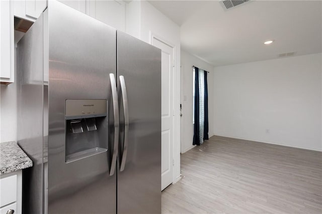 13245 Wrangler St, Robstown, TX 78380 - kitchen featuring white cabinets, stainless steel fridge, light wood-style flooring, and visible vents