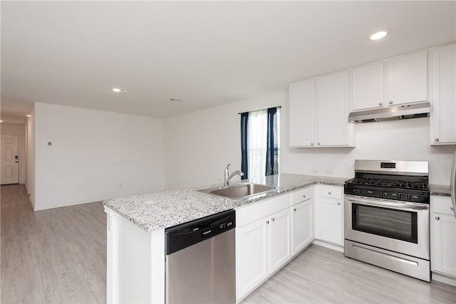 13245 Wrangler St, Robstown, TX 78380 - kitchen with under cabinet range hood, light wood finished floors, a sink, a peninsula, and appliances with stainless steel finishes