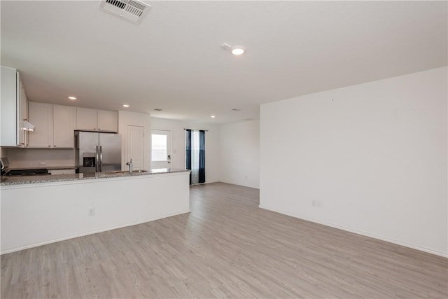 13245 Wrangler St, Robstown, TX 78380 - kitchen with light stone countertops, light wood-style flooring, stainless steel refrigerator with ice dispenser, and visible vents