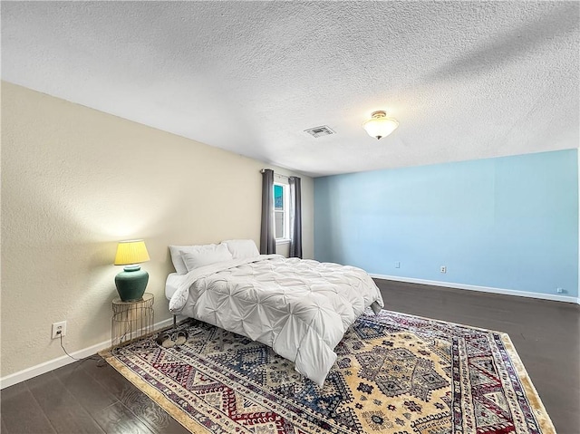 bedroom featuring visible vents, dark wood-style flooring, baseboards, and a textured ceiling