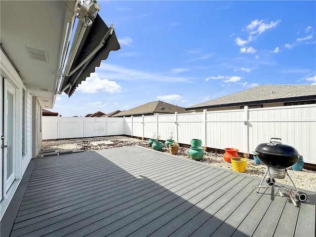 wooden deck featuring visible vents, a fenced backyard, and a grill