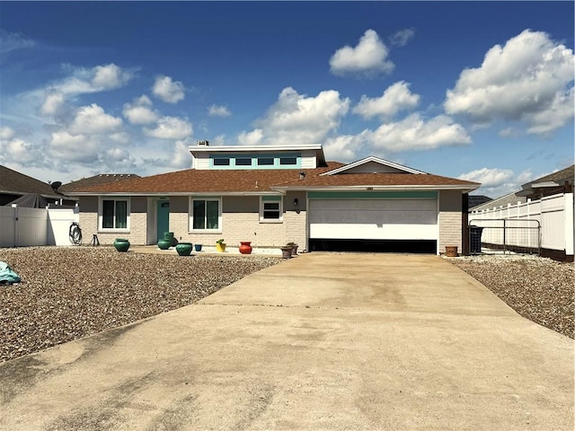 view of front of home featuring driveway, a garage, fence, and brick siding
