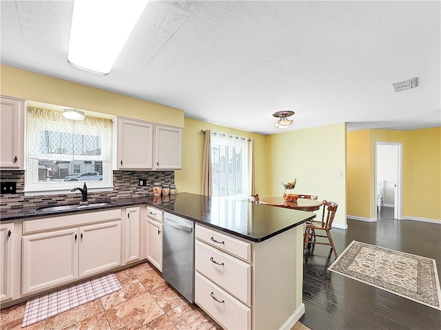 kitchen featuring stainless steel dishwasher, a sink, visible vents, and a wealth of natural light