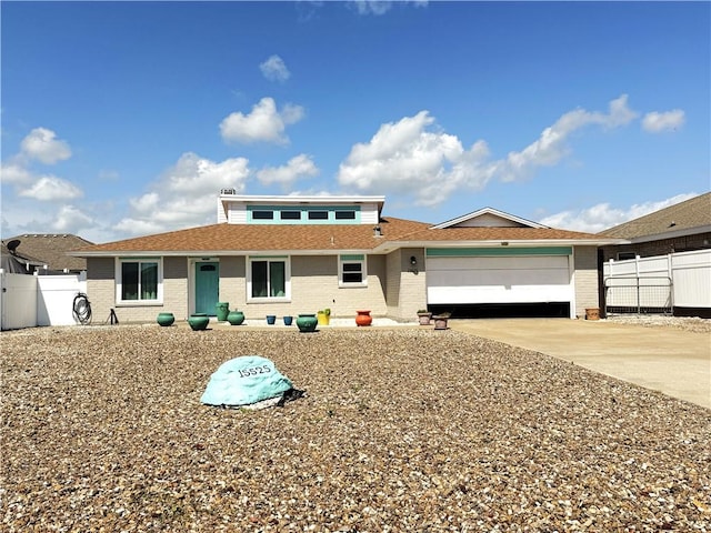 prairie-style home with brick siding, driveway, fence, and an attached garage