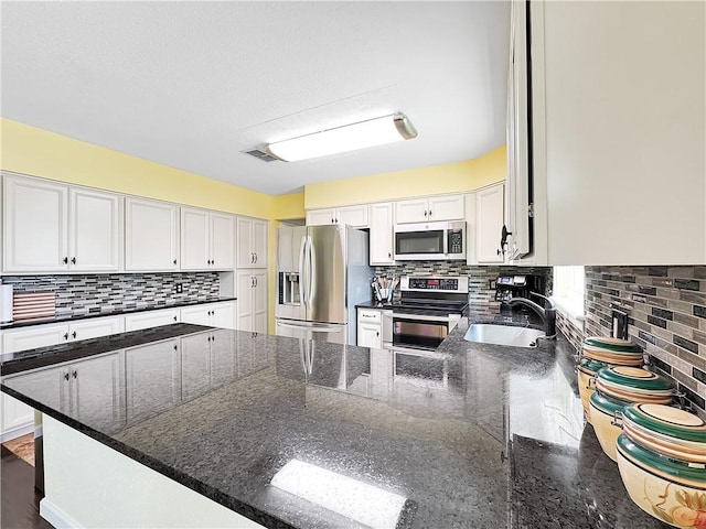 kitchen featuring tasteful backsplash, a sink, white cabinets, and stainless steel appliances