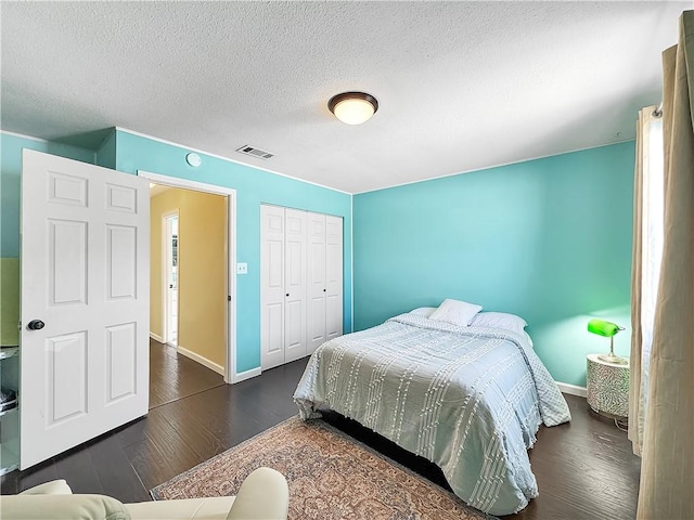 bedroom with dark wood-type flooring, visible vents, baseboards, and a textured ceiling