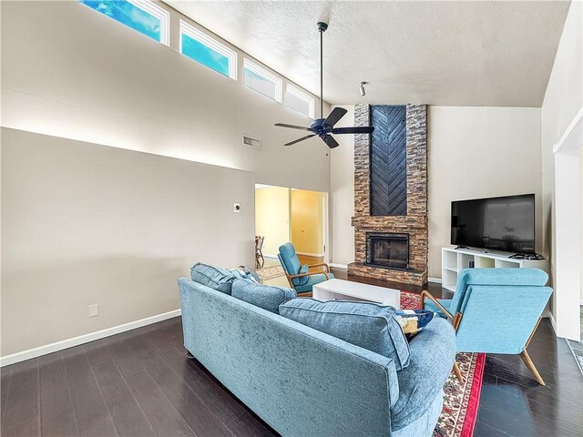 living area featuring ceiling fan, a fireplace, dark wood finished floors, visible vents, and baseboards