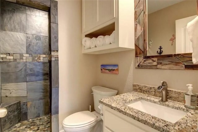 full bath featuring toilet, tiled shower, and vanity