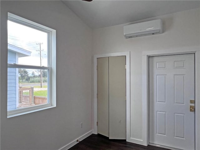 unfurnished bedroom featuring lofted ceiling, dark wood-type flooring, and a wall mounted air conditioner