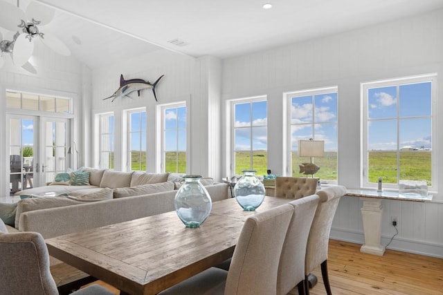 dining area featuring light wood-style flooring, visible vents, vaulted ceiling, and french doors