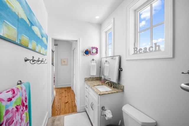 bathroom featuring baseboards, vanity, toilet, and wood finished floors