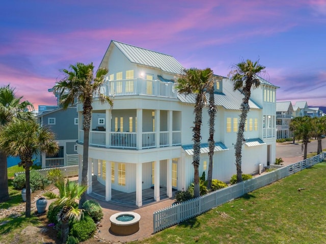 back of property with a balcony, fence private yard, a patio area, and a standing seam roof