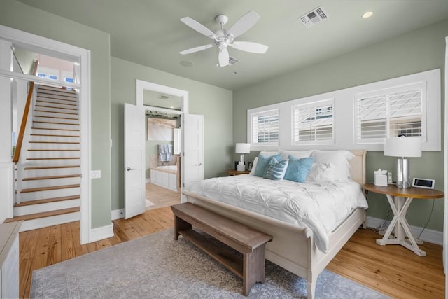 bedroom with baseboards, visible vents, ceiling fan, wood finished floors, and ensuite bathroom